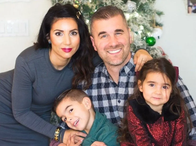 Christmas portrait with Lydia and their two children. Nicholas Jacobs and his family in front of a decorated Christmas tree.